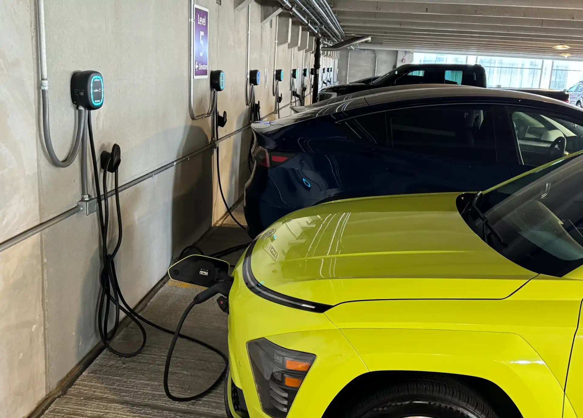 Wallbox Chargers mounted on garage wall plugged into cars charging.