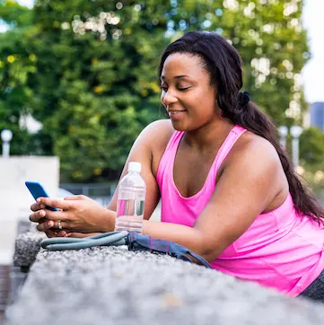 A woman on her phone after finishing a run