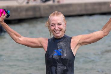Mary Haffner Holloway lifts her arms in celebration after participating in Swim Across America's Chicago Open Water Swim.