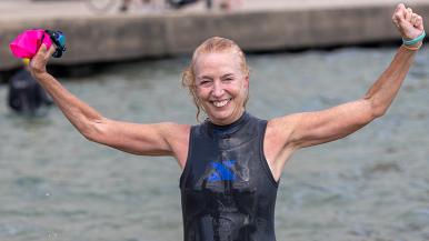 Mary Haffner Holloway lifts her arms in celebration after participating in Swim Across America's Chicago Open Water Swim.