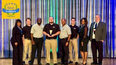 A group of students and faculty members standing on a stage holding an award