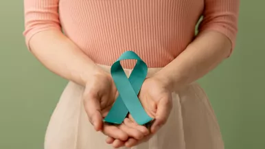 A woman holds a cervical cancer awareness ribbon