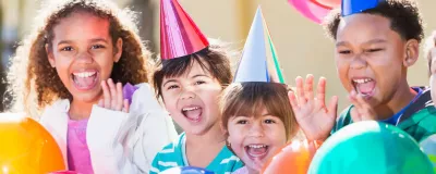 Kids wearing birthday hats holding balloons